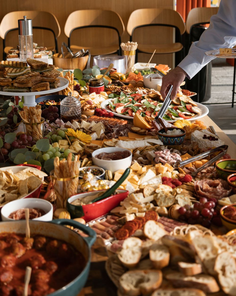 Elaborate charcuterie board spread with meats, cheeses, and appetizers on a wooden table.