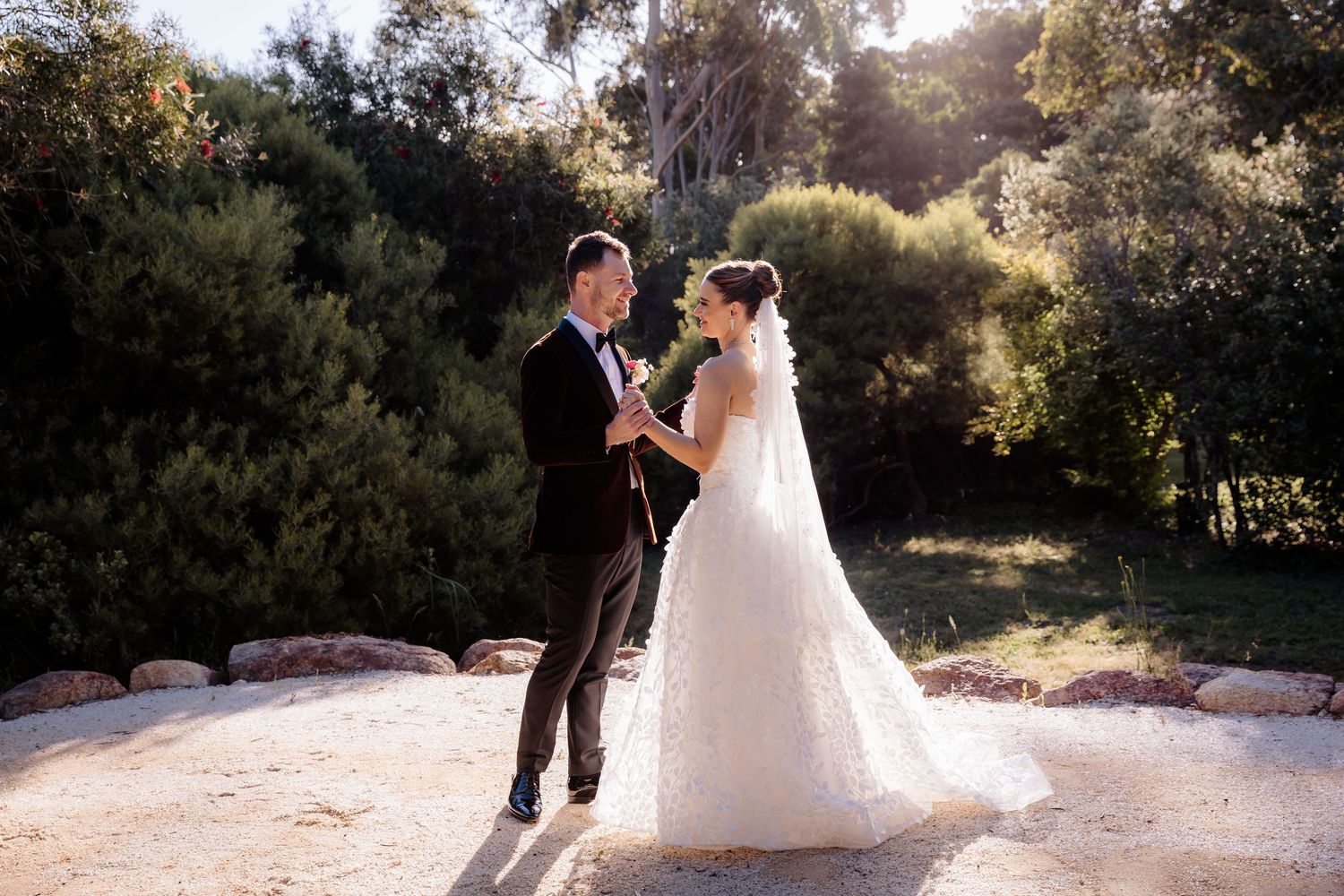 Elegant couple poses against a tree backdrop in vintage-inspired formal wear.