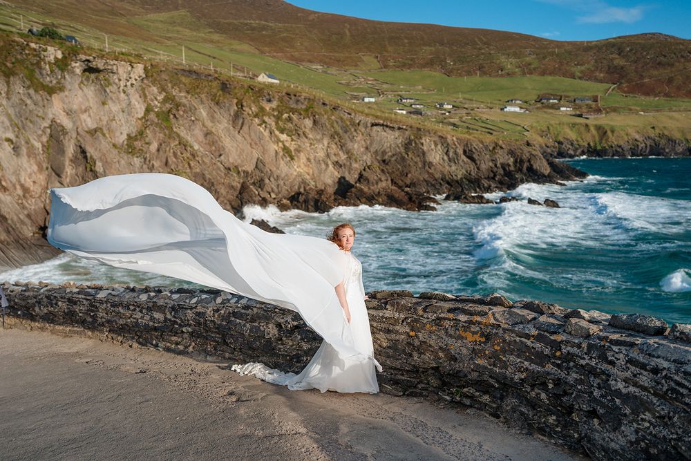 Dramatic coastal landscape with rocky cliffs and crashing waves against a rugged Irish shoreline on a sunny day.