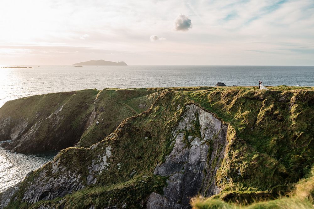 Rugged coastal cliffs rise dramatically from the ocean under a cloudy sky along the Irish coastline.
