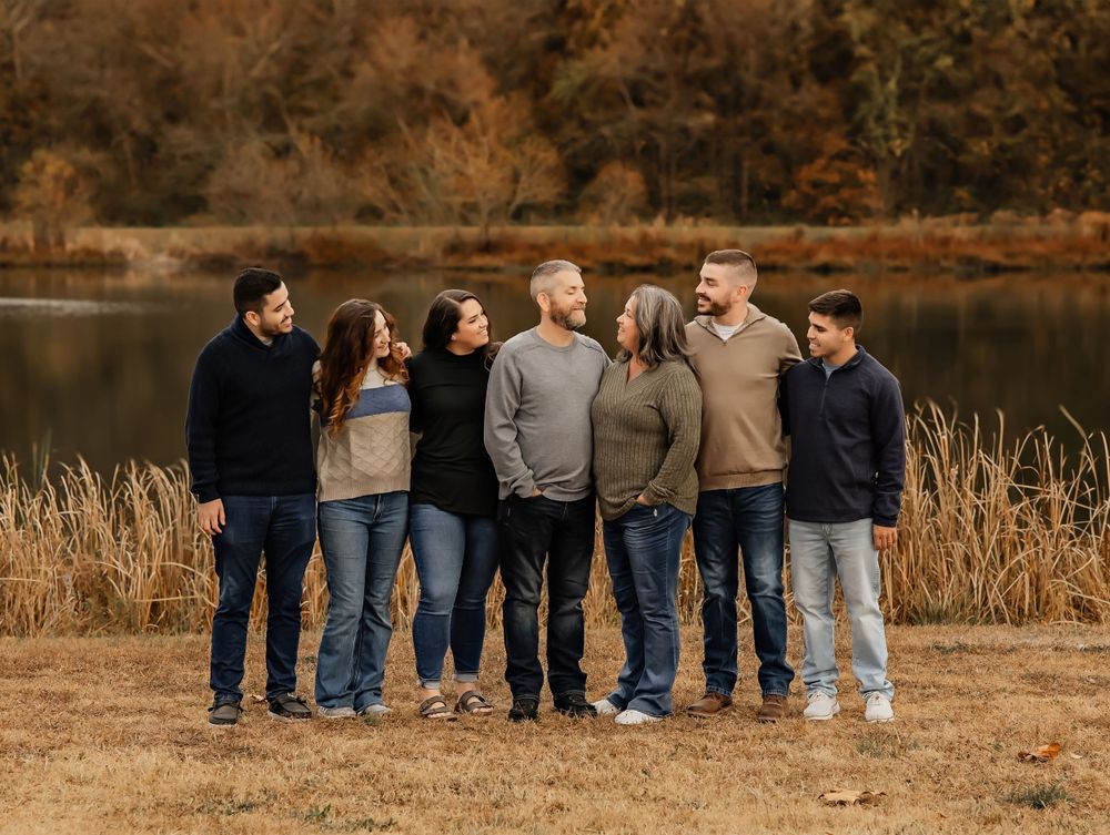 A group in coordinated outfits walks together along a grassy field during golden hour.