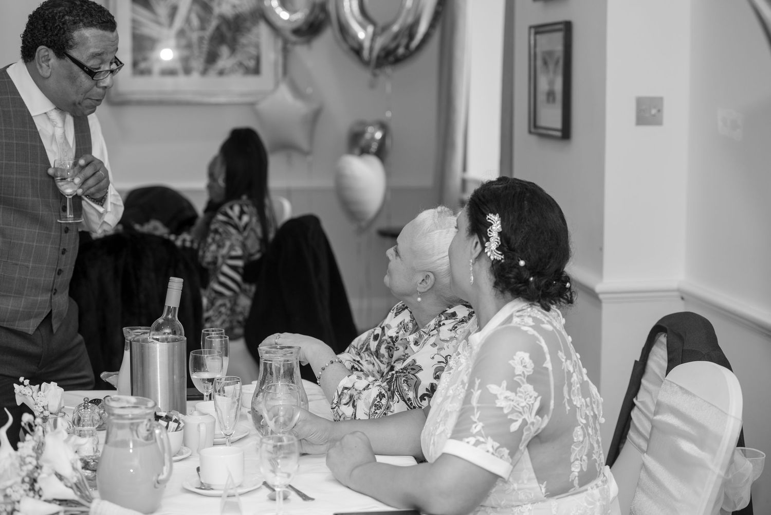 Wedding reception guests enjoying conversation at decorated dining table.