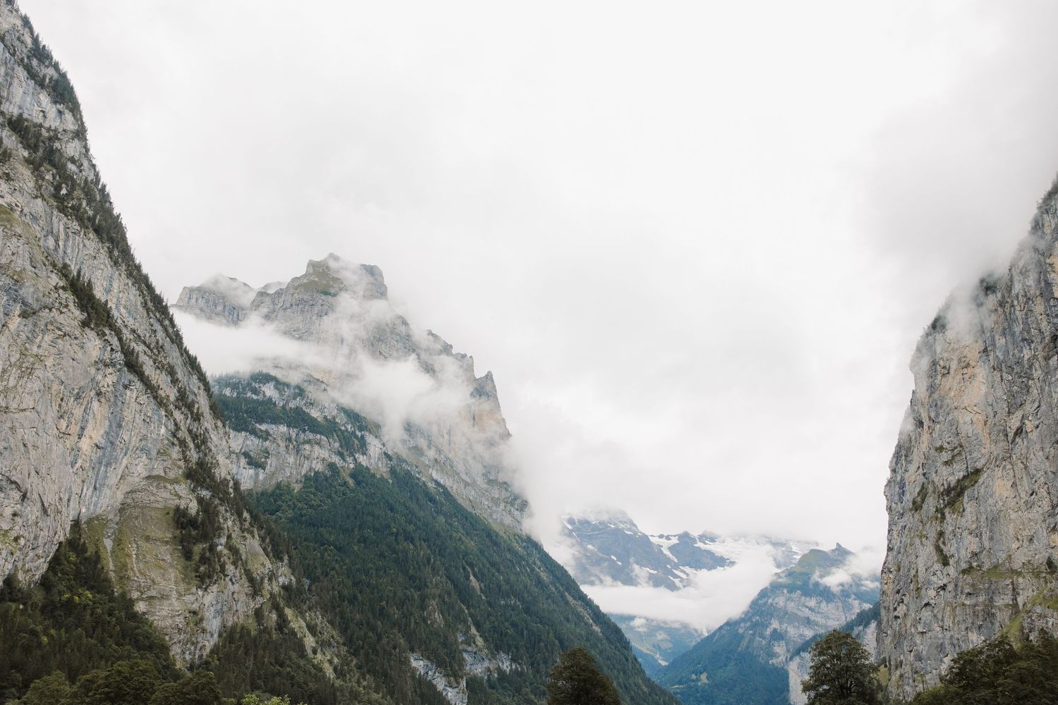 Dramatic mountain landscape with misty peaks and cloudy sky in alpine valley.