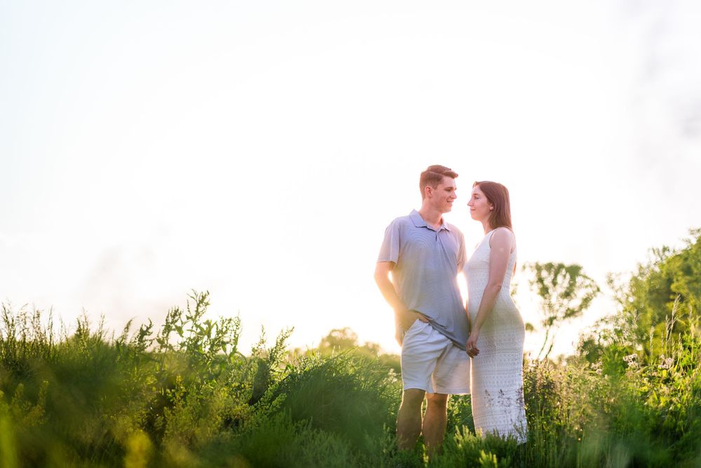 A couple shares a tender moment in a sunlit meadow during golden hour.