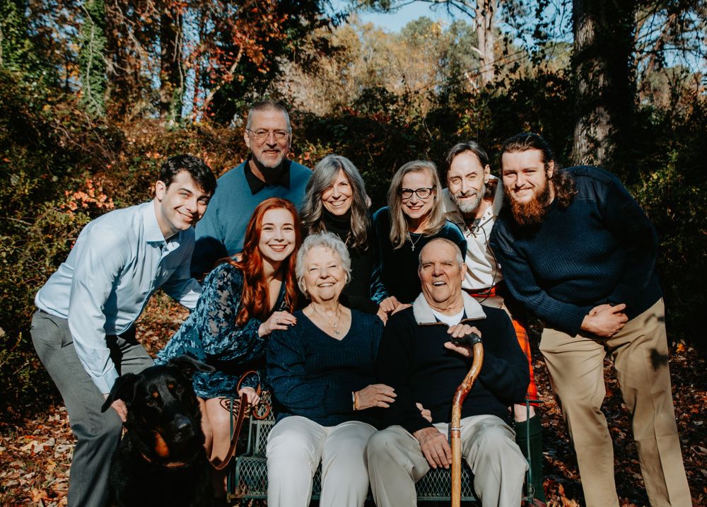 Smiling family posed together outdoors, capturing a warm and candid moment during a portrait session