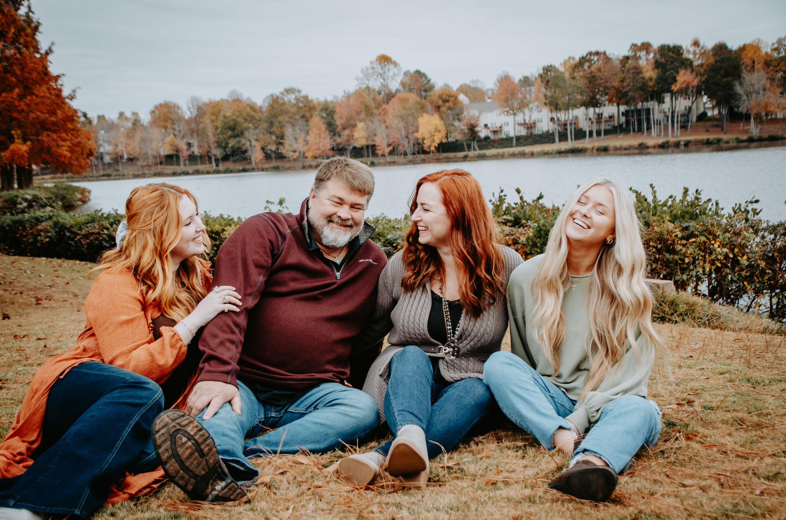 Smiling family posed together outdoors, capturing a warm and candid moment during a portrait session