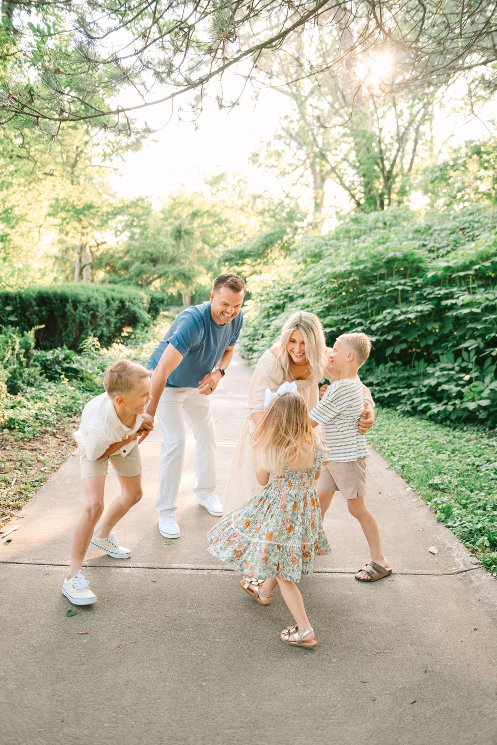 A playful family photo sequence showing parents and children dancing together on a garden path.