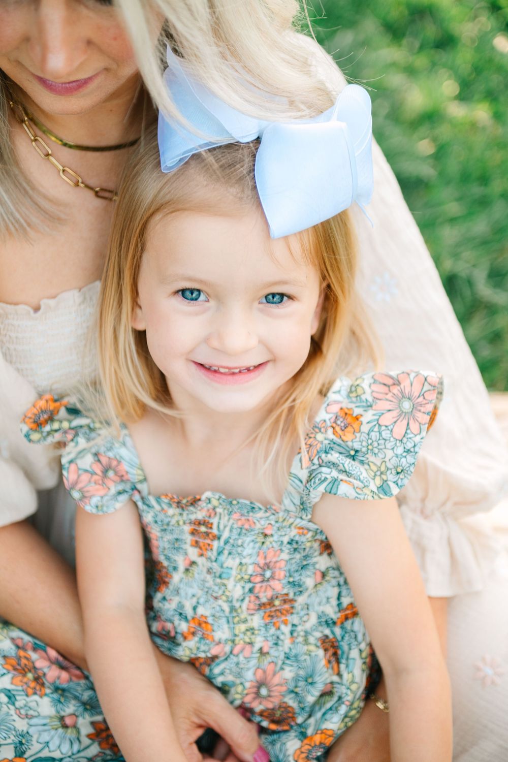 Close-up portrait showing soft details of a floral dress and blonde hair.