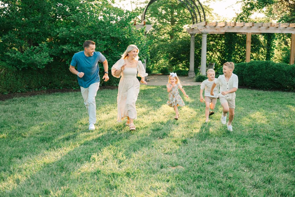 People playing and running together on a grassy hillside during golden hour in a park setting.