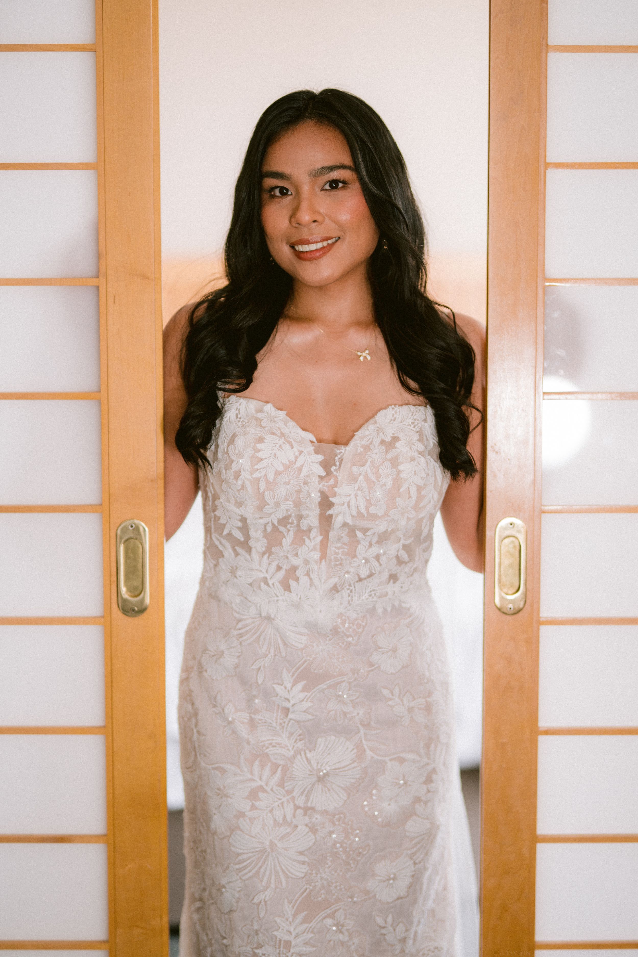 A person wearing a white lace dress poses in front of traditional Japanese shoji sliding doors.