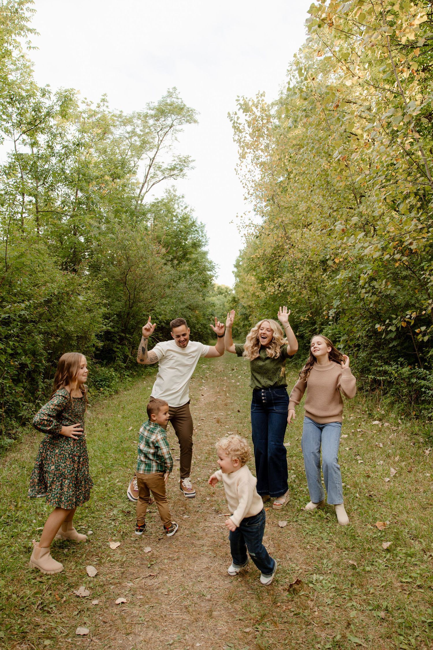 Family group walking and playing together on a wooded trail during autumn.