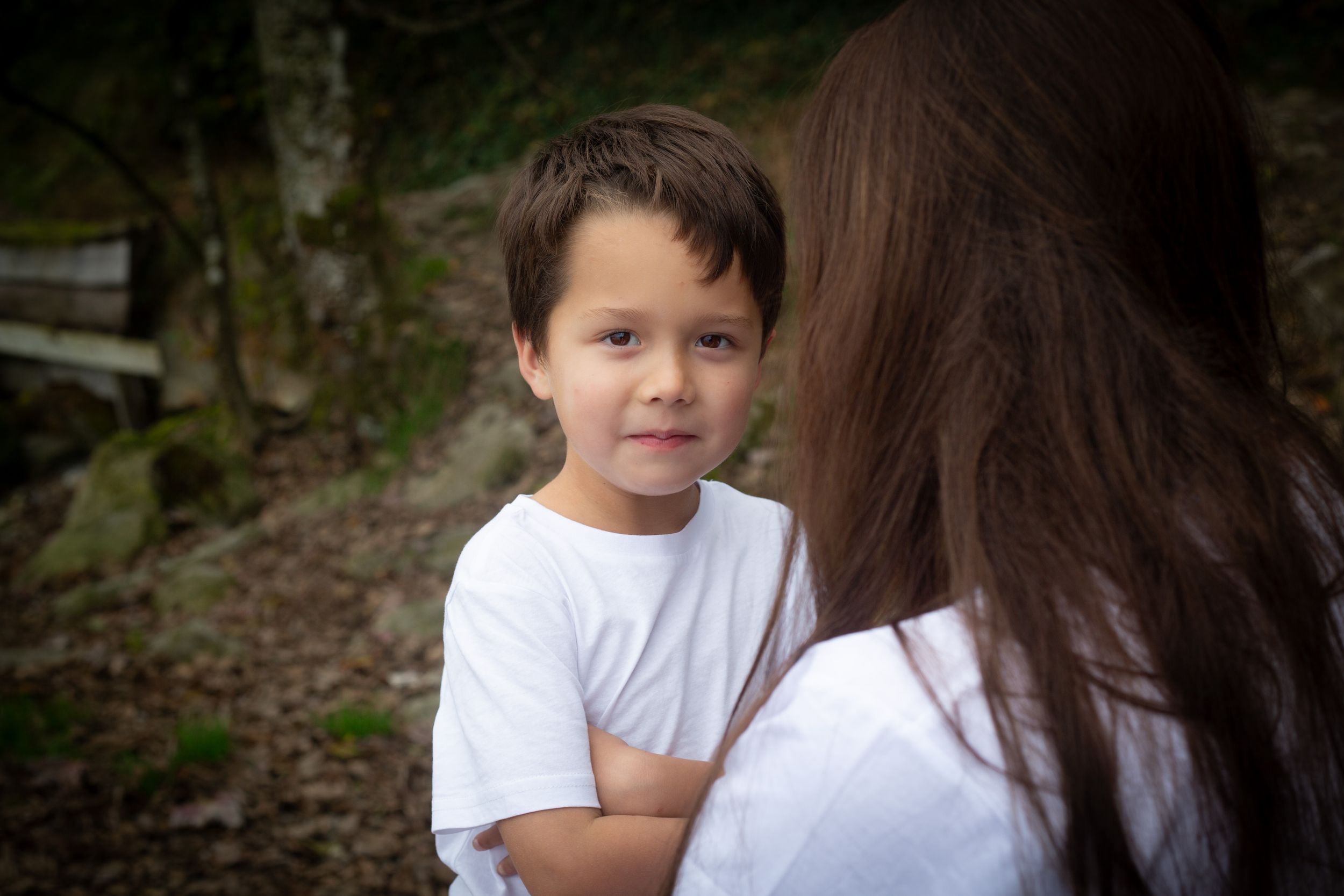 Family portrait scene outdoors with gentle interaction between two people wearing white shirts.