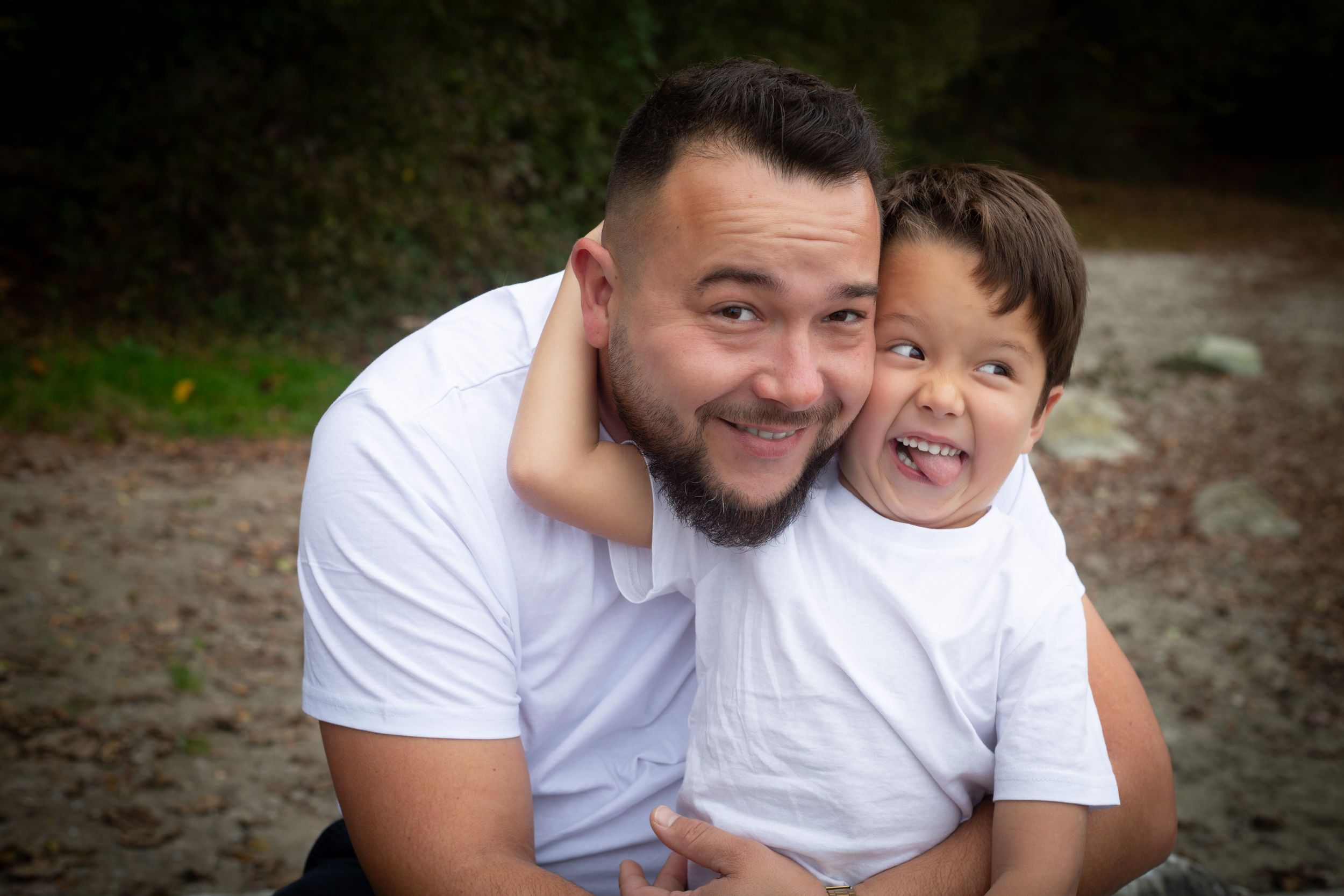 Joyful moment captured outdoors showing affectionate embrace in matching white t-shirts.
