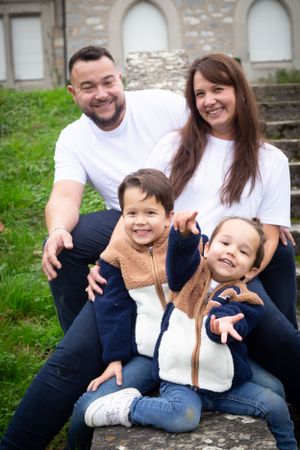 Family portrait with matching outfits sitting on stone steps near historic building.