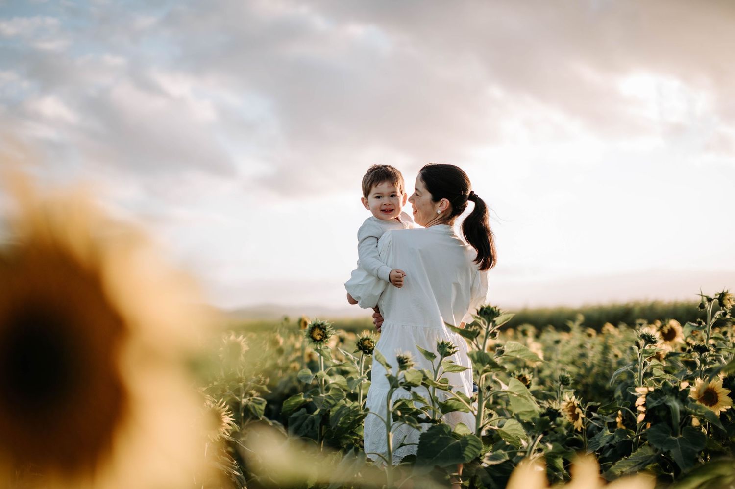 Silhouette of parent lifting child against dramatic sunset sky.