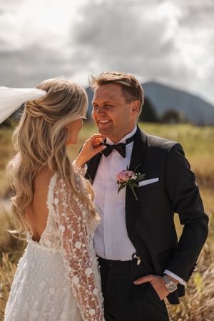 Couple share joyful moments together in a scenic mountain field during their wedding photoshoot.