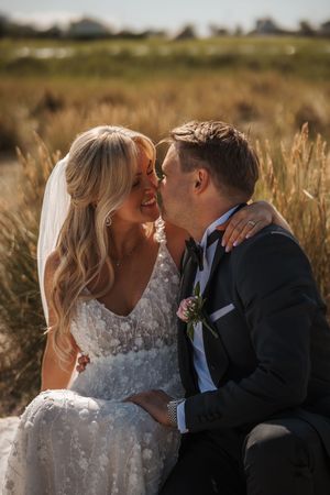 A joyful couple shares an intimate moment in a golden wheat field on their wedding day.