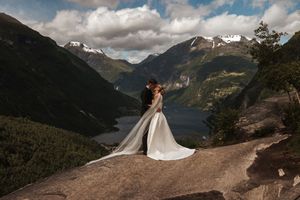 Couple in wedding attire silhouetted against a dramatic mountain lake landscape in Norway.