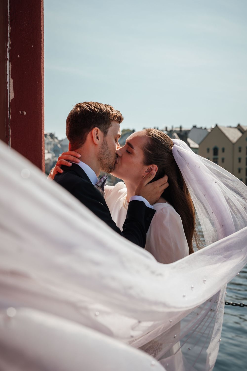 A romantic wedding photo sequence showing a bride's veil flowing gracefully in the wind as the newlyweds kiss.