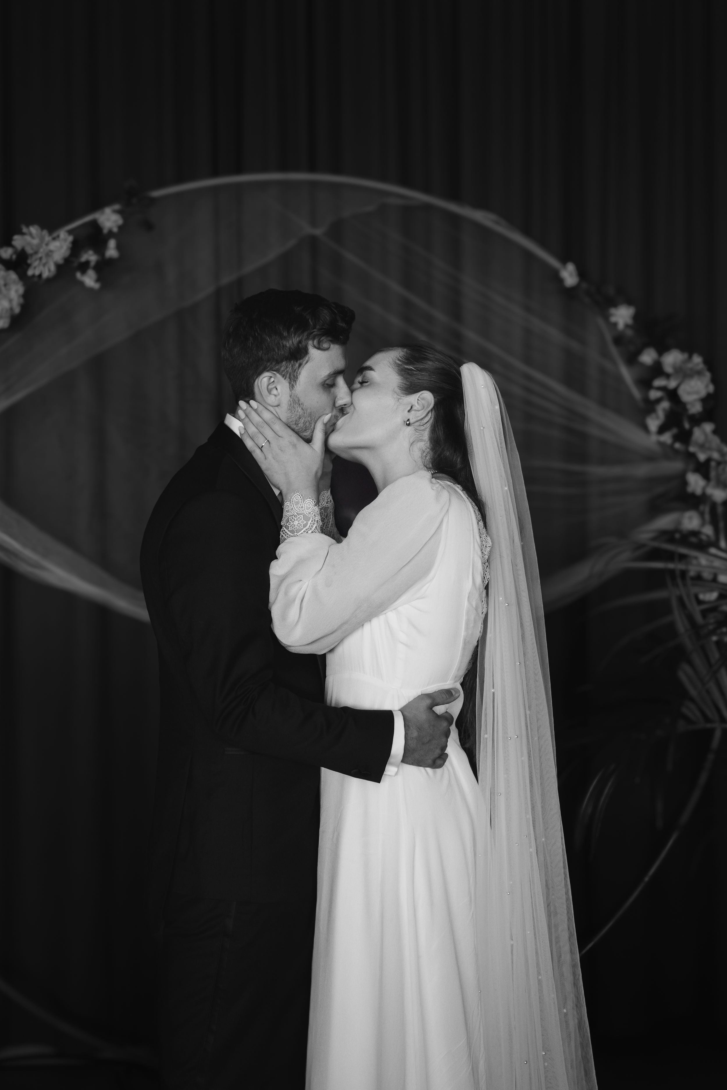 A romantic black and white wedding photograph series showing the couple sharing a kiss while the bride wears a long flowing veil.