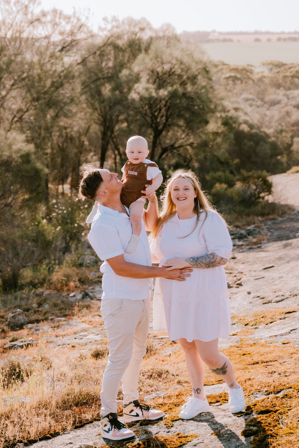 Family sharing tender moments during outdoor desert photoshoot in matching white attire.