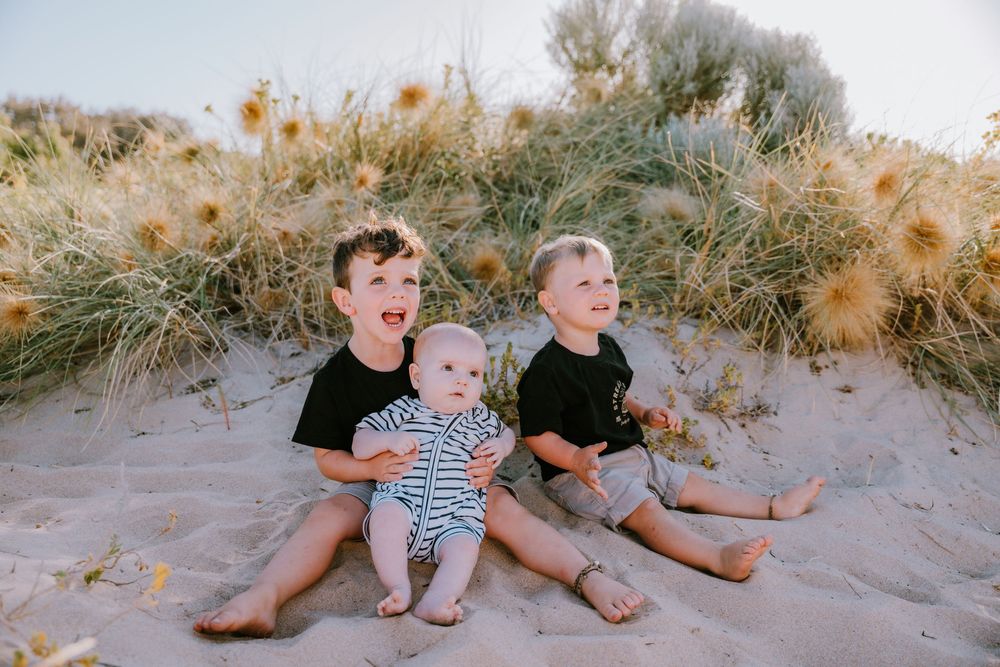 Family members relaxing together on sandy beach dunes.