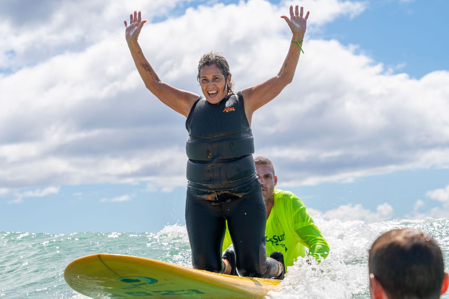 People raising arms in celebration during sunny outdoor beach activity.