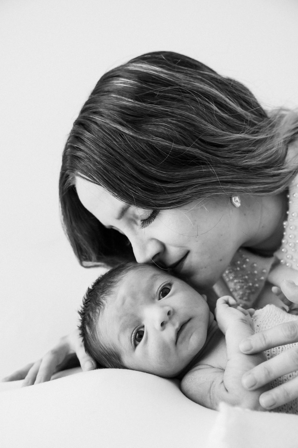 Intimate black and white portrait of parent and baby sharing a tender moment.