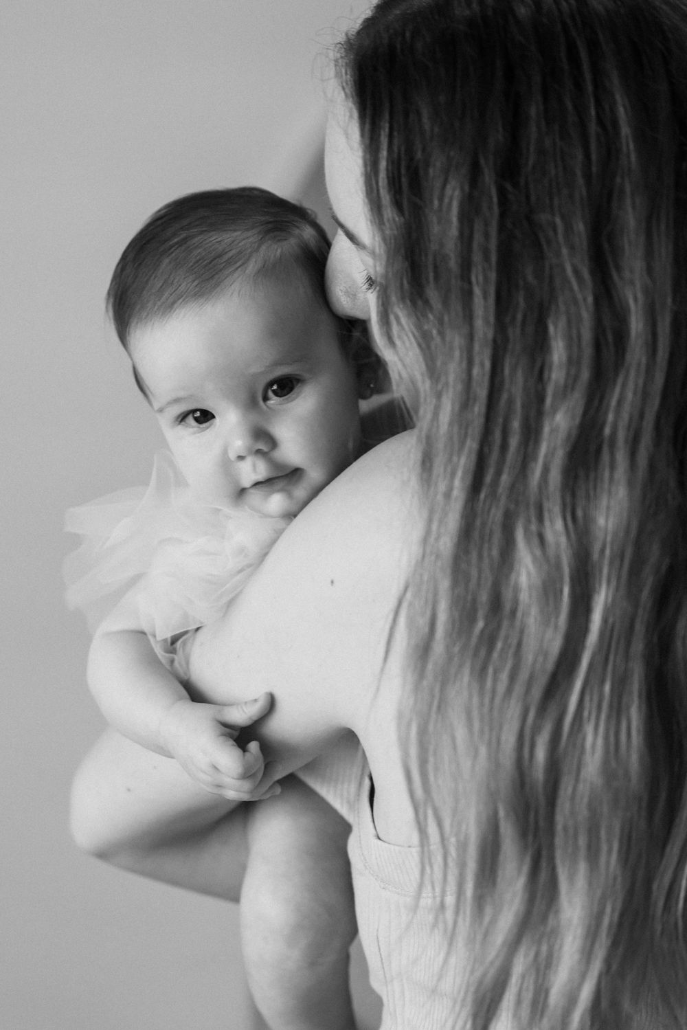 Black and white portrait capturing intimate moment between parent and baby.