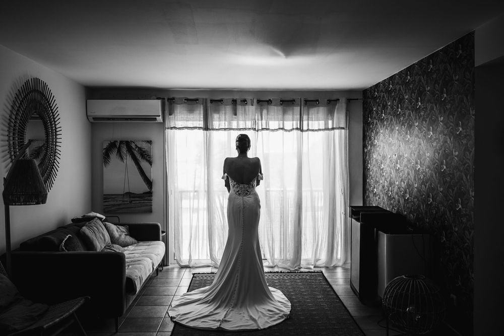 A dramatic black and white photo series showing a wedding dress in various interior settings with moody lighting.