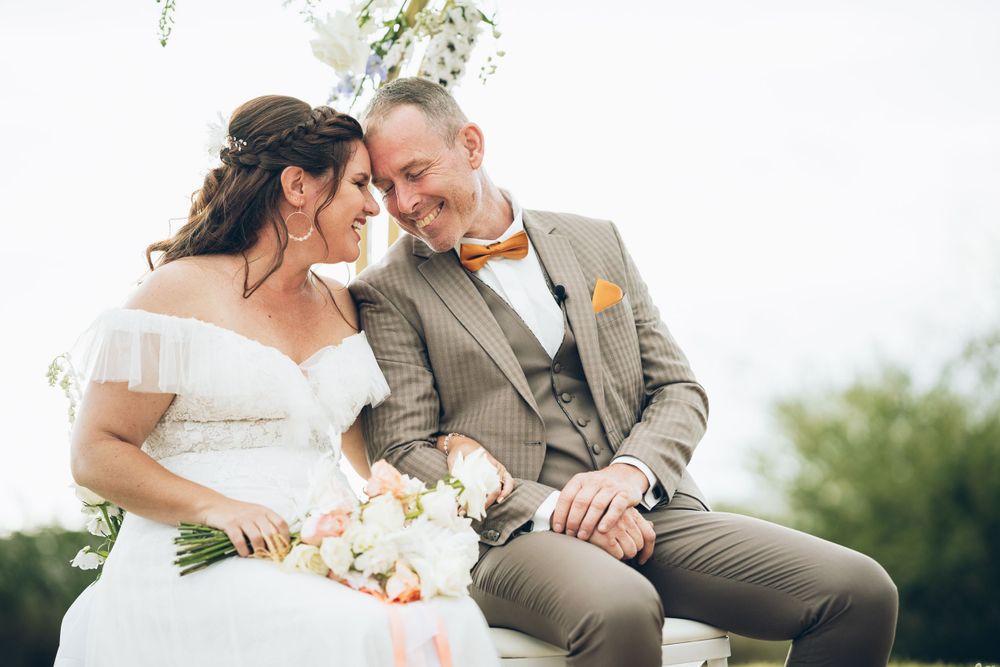Intimate wedding portrait of newlyweds sharing tender moment outdoors.