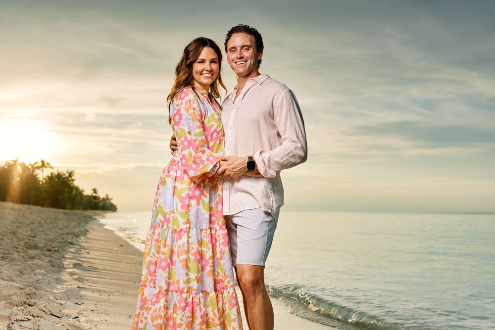 Romantic beach portrait of couple in coordinated pastel outfits at sunset.