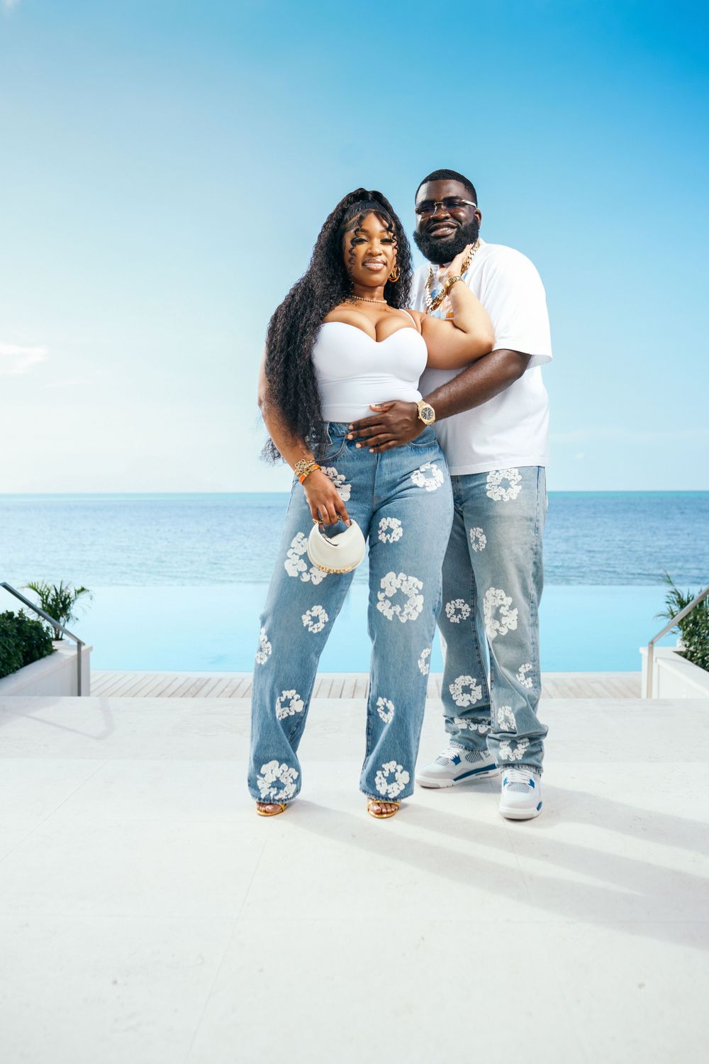 Happy couple in matching floral denim poses on oceanfront terrace.