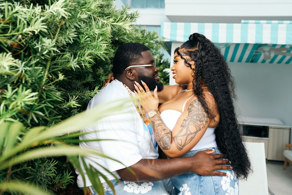 Couple embracing in tropical garden setting wearing casual white outfits.