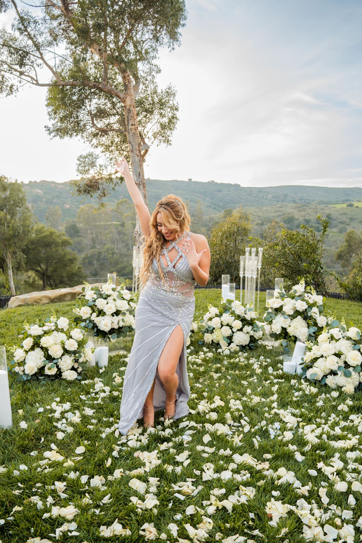 An elegant outdoor portrait session in a field of white flowers with mountains visible in the distance.