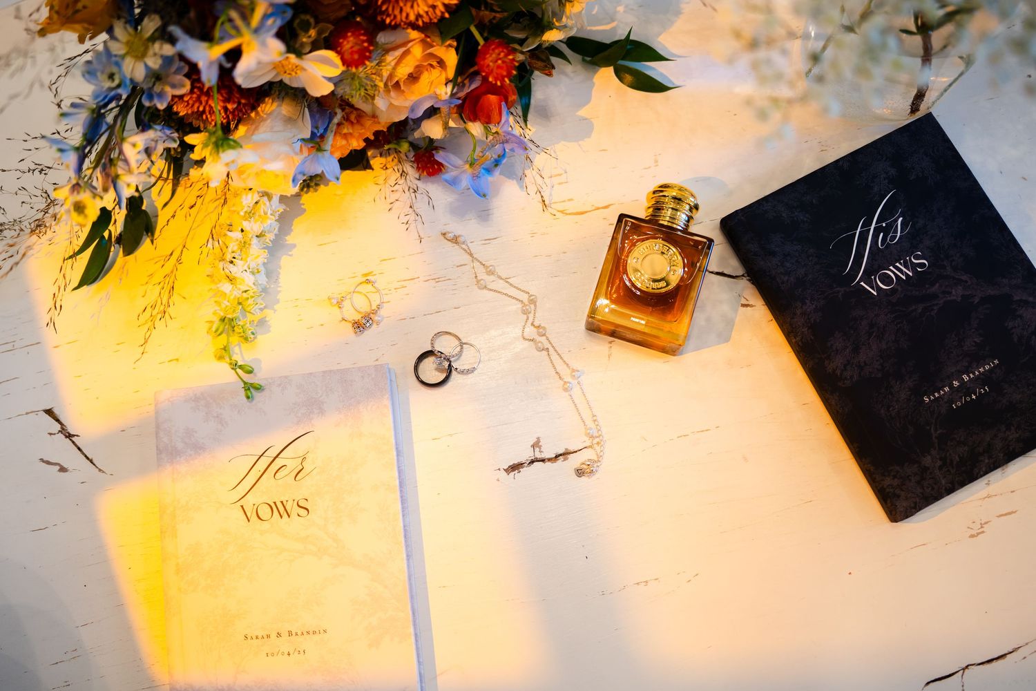 A perfume bottle and black box displayed on a light surface with colorful floral decorations and paper elements.