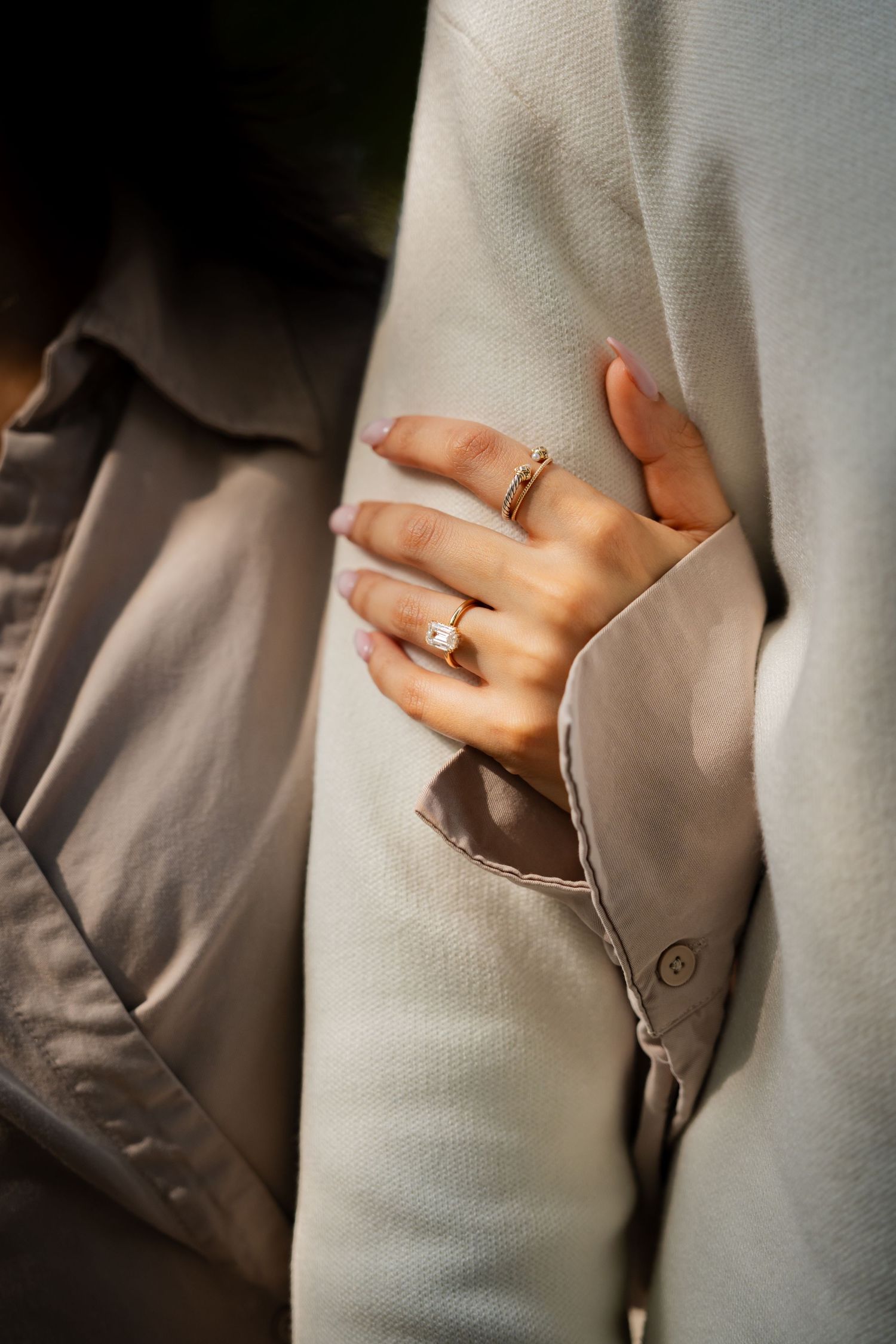 Close-up view of hands showing an engagement ring against a light gray fabric background.