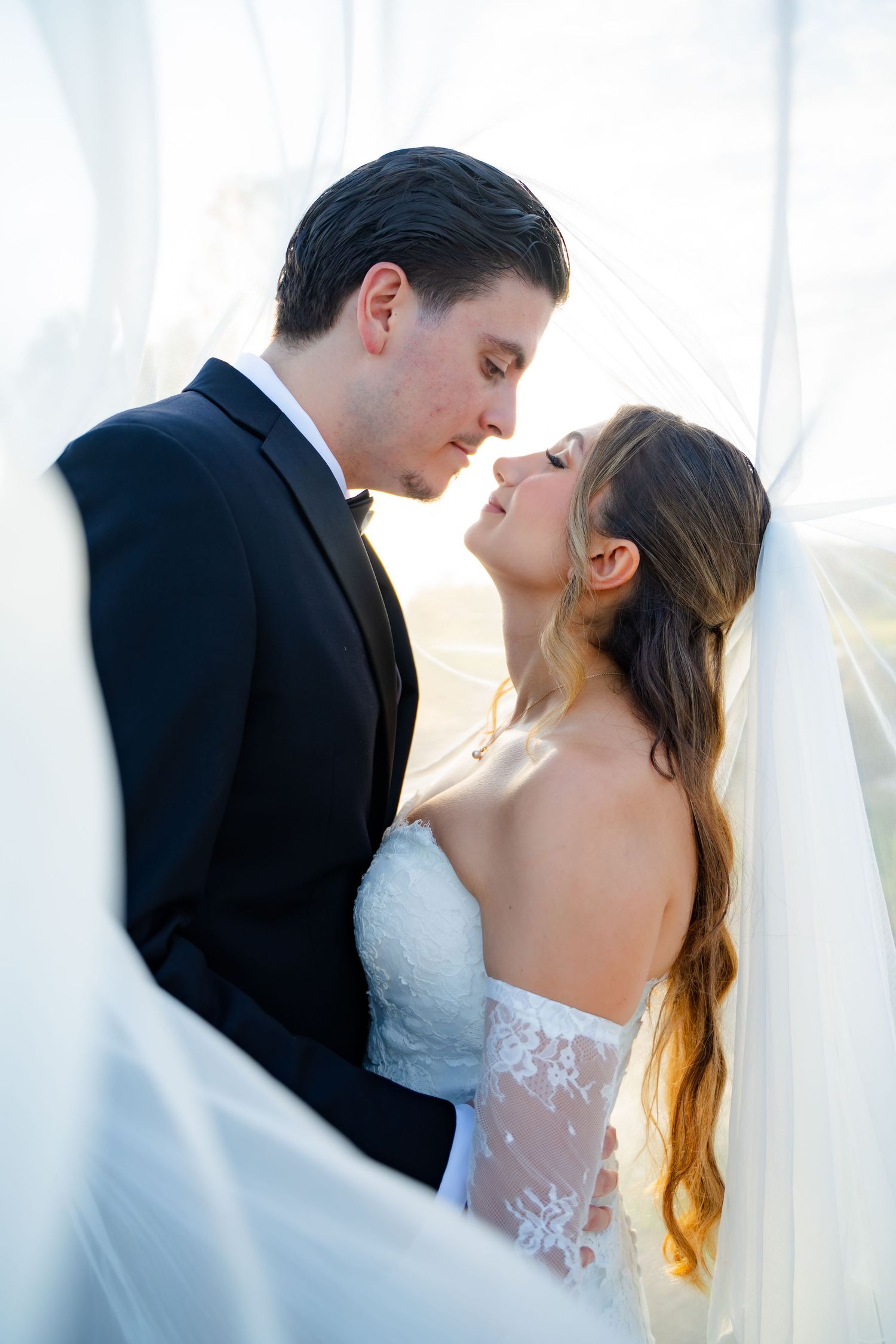 A romantic wedding couple embraces near sheer white curtains in three similar poses.