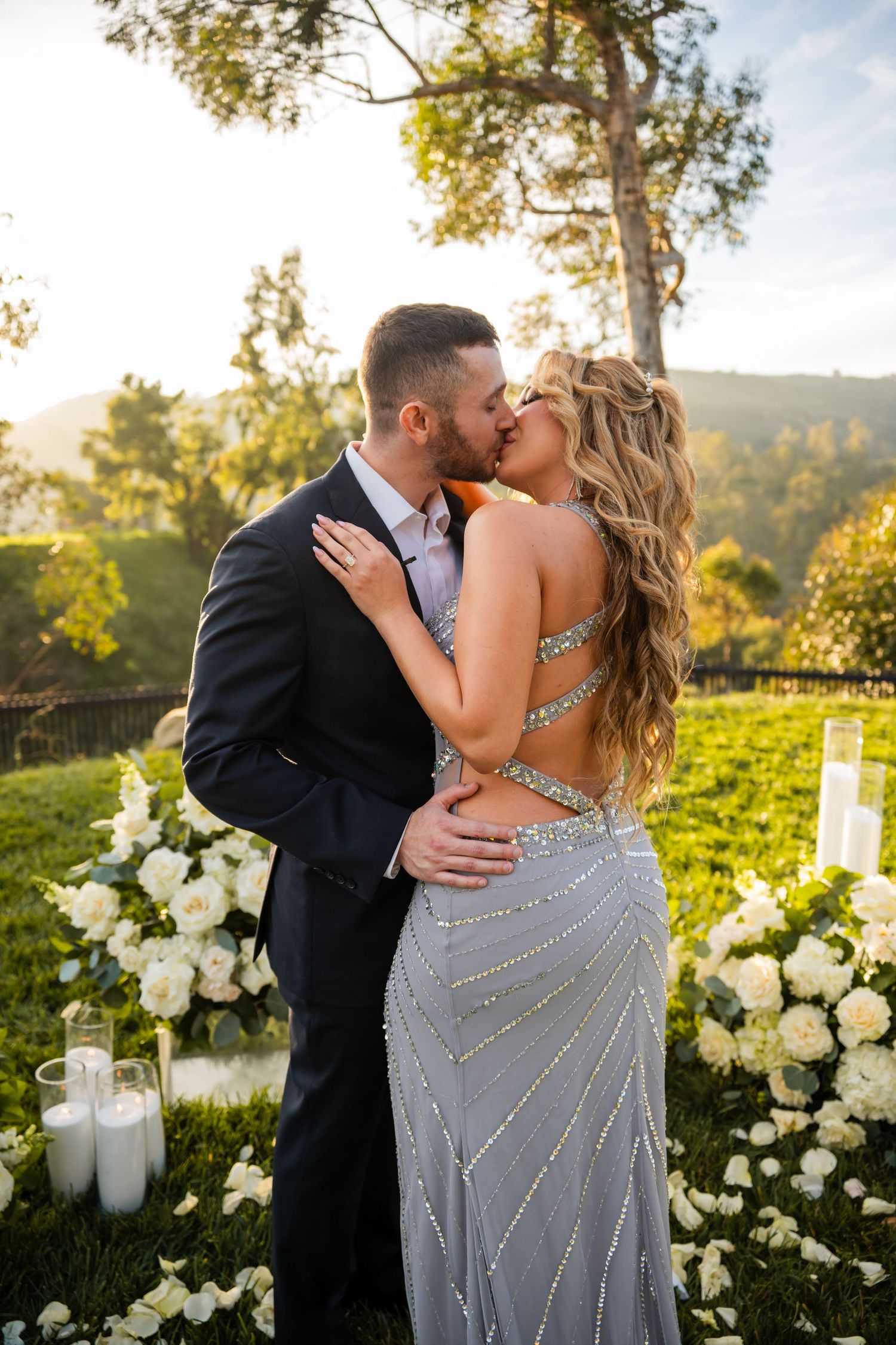 A romantic sunset photoshoot in a garden with white floral arrangements and glowing candles.