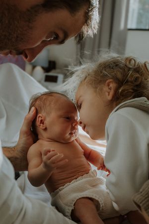A tender moment between parent and newborn baby in soft natural light.