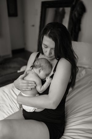 Intimate black and white photo series showing tender moments between parent and infant on white bedding.
