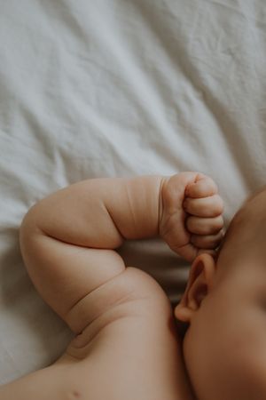 Close-up photo of tiny baby feet and toes against white fabric textured background.