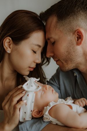 Couple lovingly bonding with their newborn baby in intimate family portrait with soft lighting.