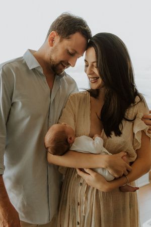A heartwarming family portrait showing parents sharing a joyful moment with their newborn baby in natural light.