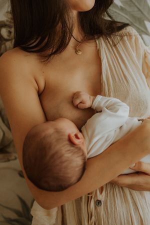 Intimate breastfeeding moment captured in warm tones as a parent nurtures their newborn in natural light.