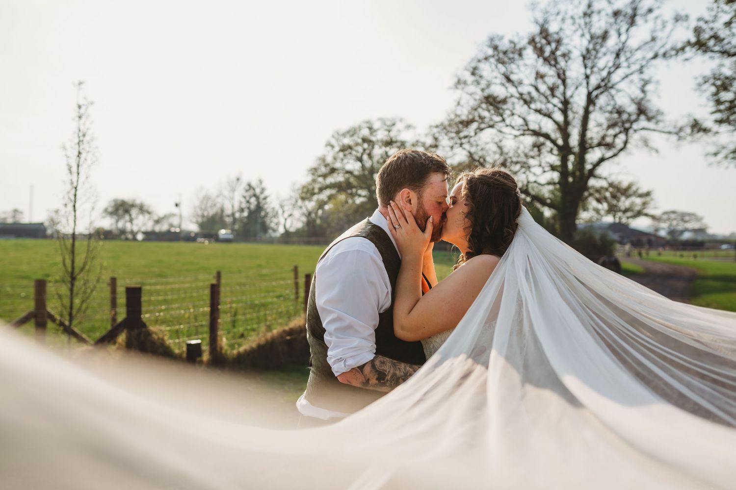 A romantic wedding couple dips and kisses in an outdoor setting.