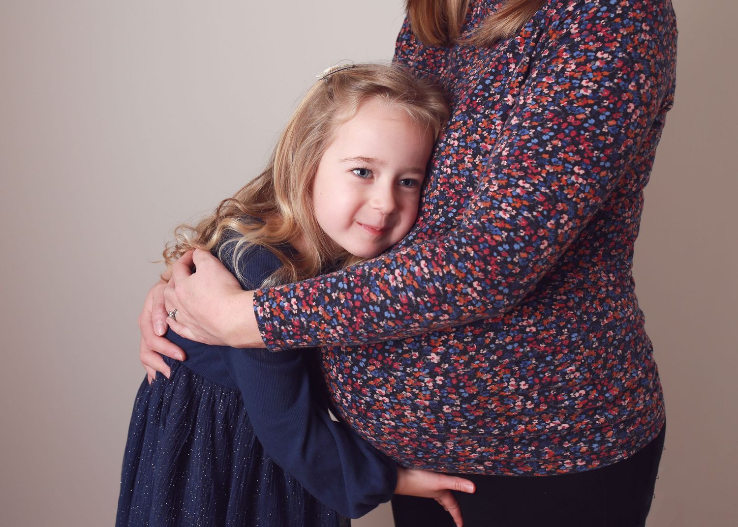 A heartfelt moment of a little girl lovingly touching her mum's pregnant belly, capturing the excitement and anticipation of her sibling