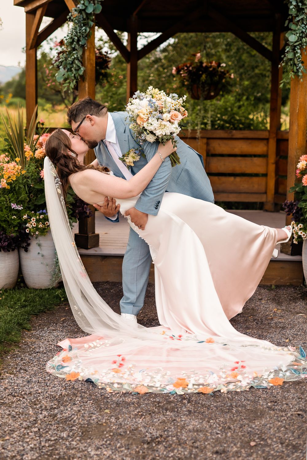 husband dip-kissing his wife at the outdoor altar at Chatfield farms
