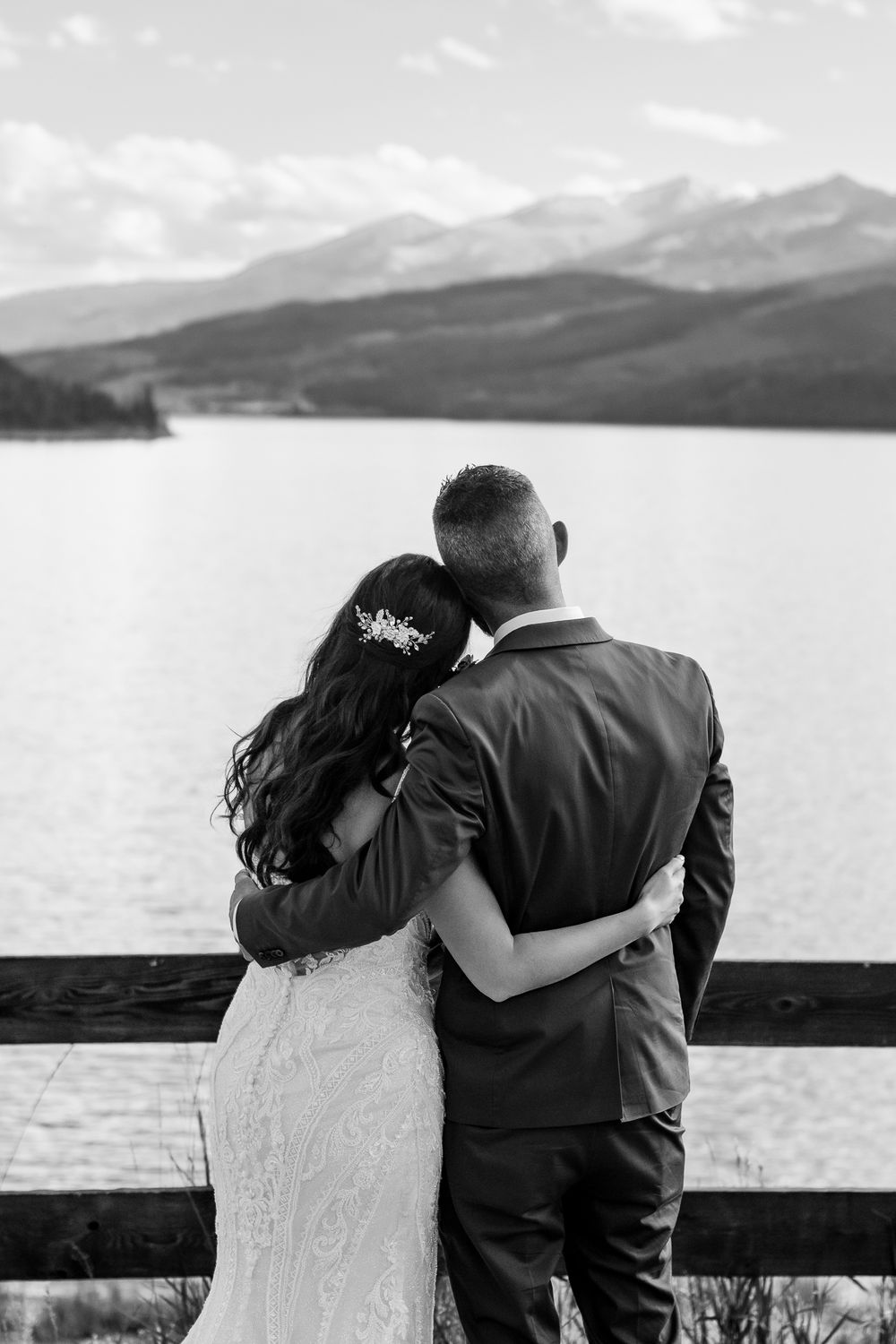 Bride and groom holding one another watching the lake at Dillon Ampitheatre