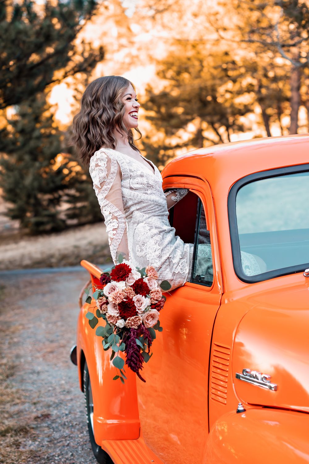 Bride laughing as she hands out of the window of a vintage GMC truck